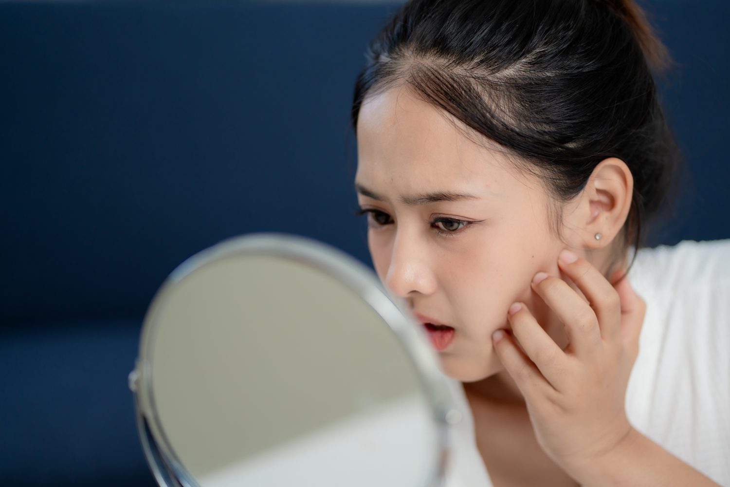 Woman checking her skin concerns in a mirror