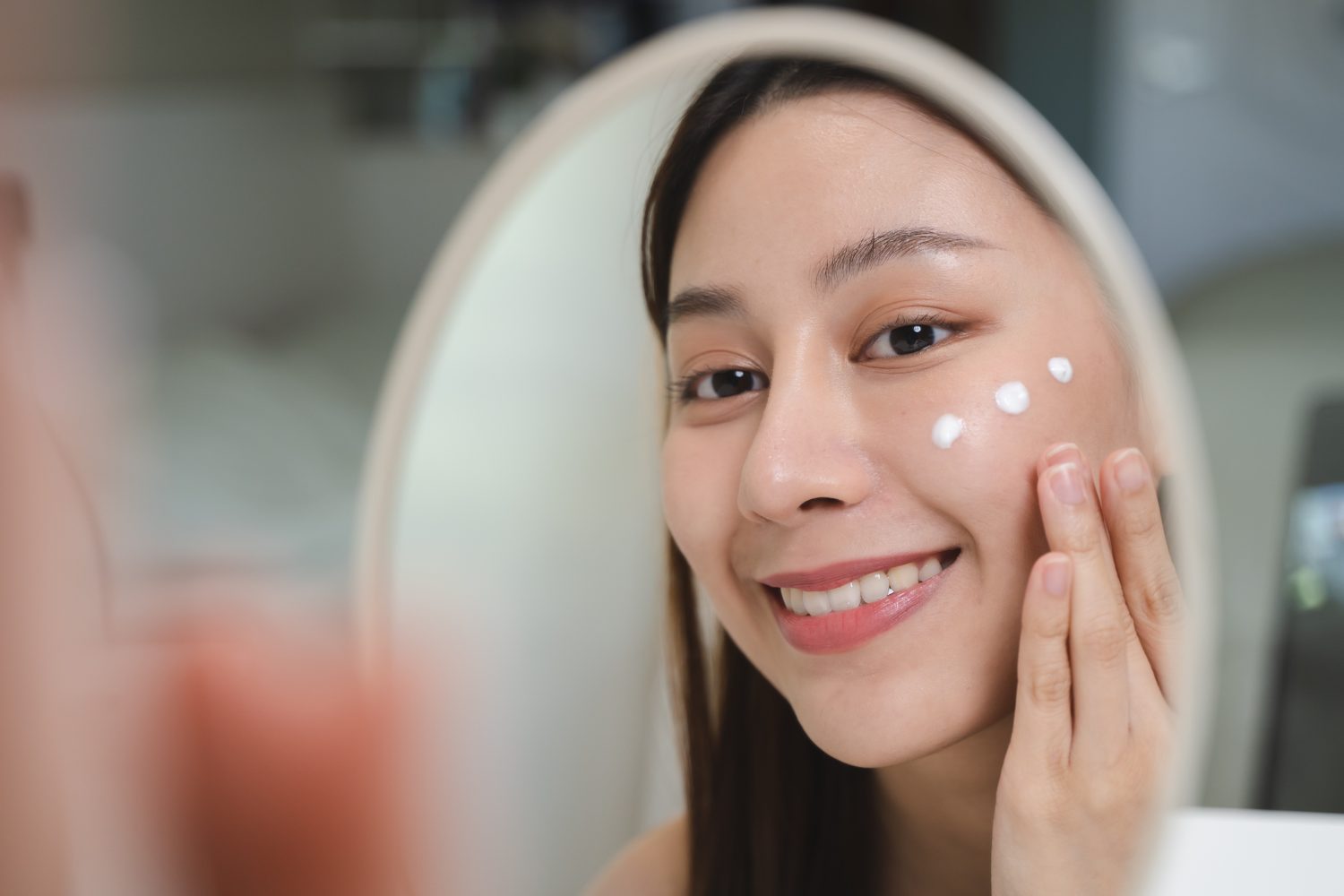 Woman applying moisturiser to her face after treatment