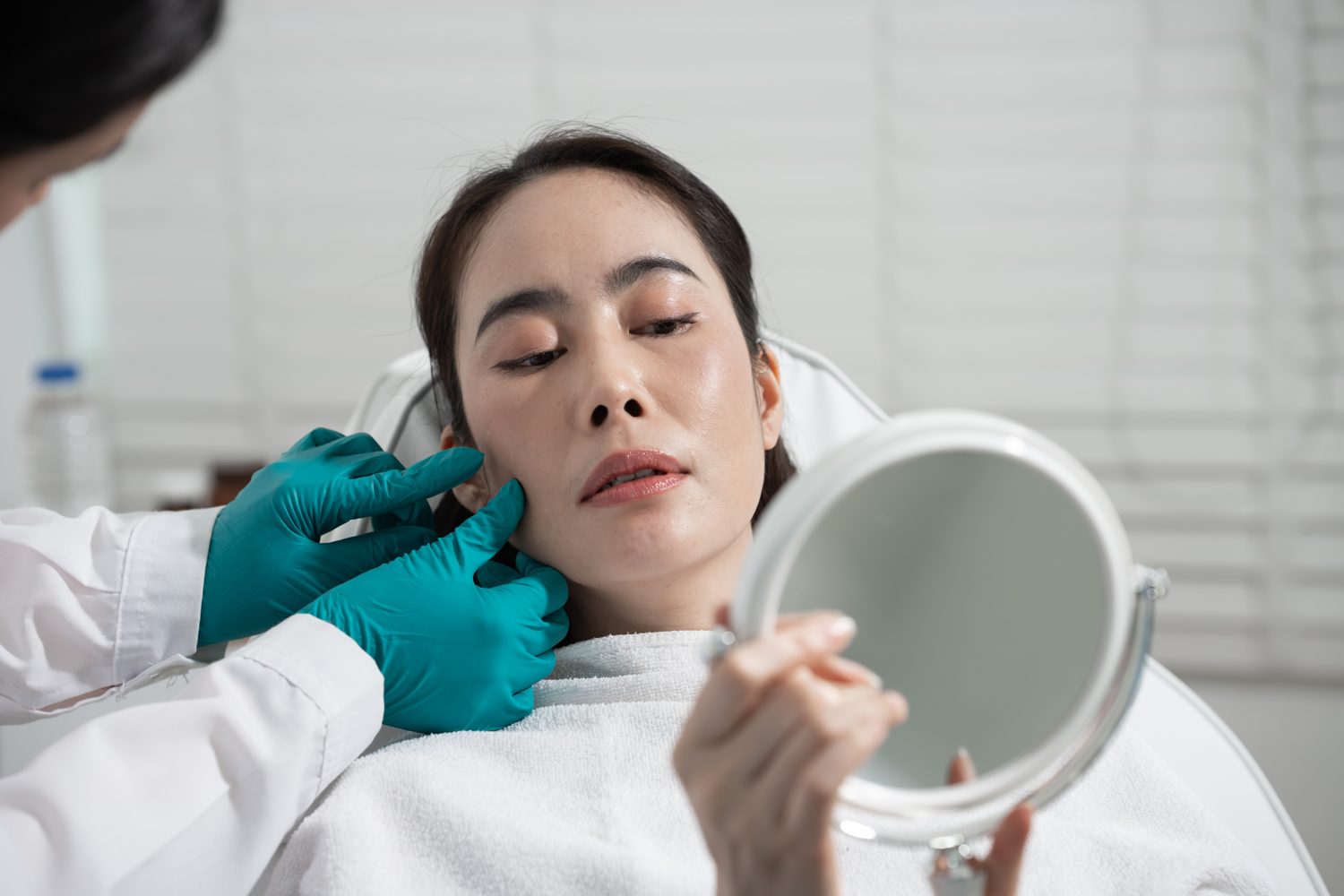 Doctor examining pigmentation on a patient's cheek during a skin assessment