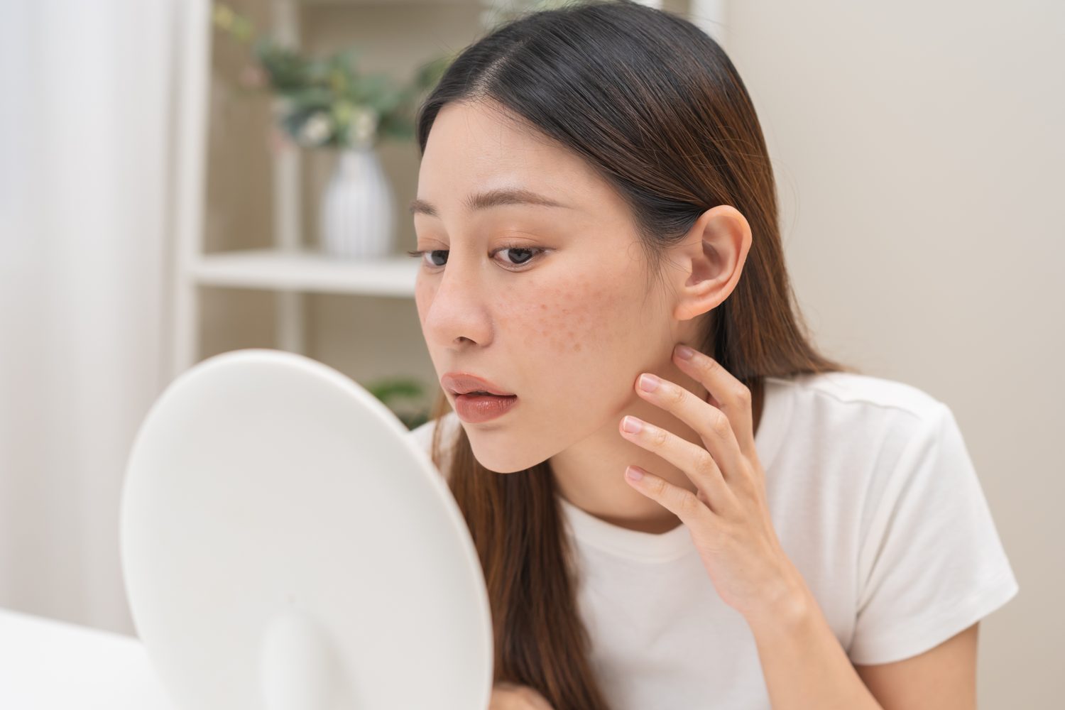 Woman checking dark spots on her cheek in a mirror