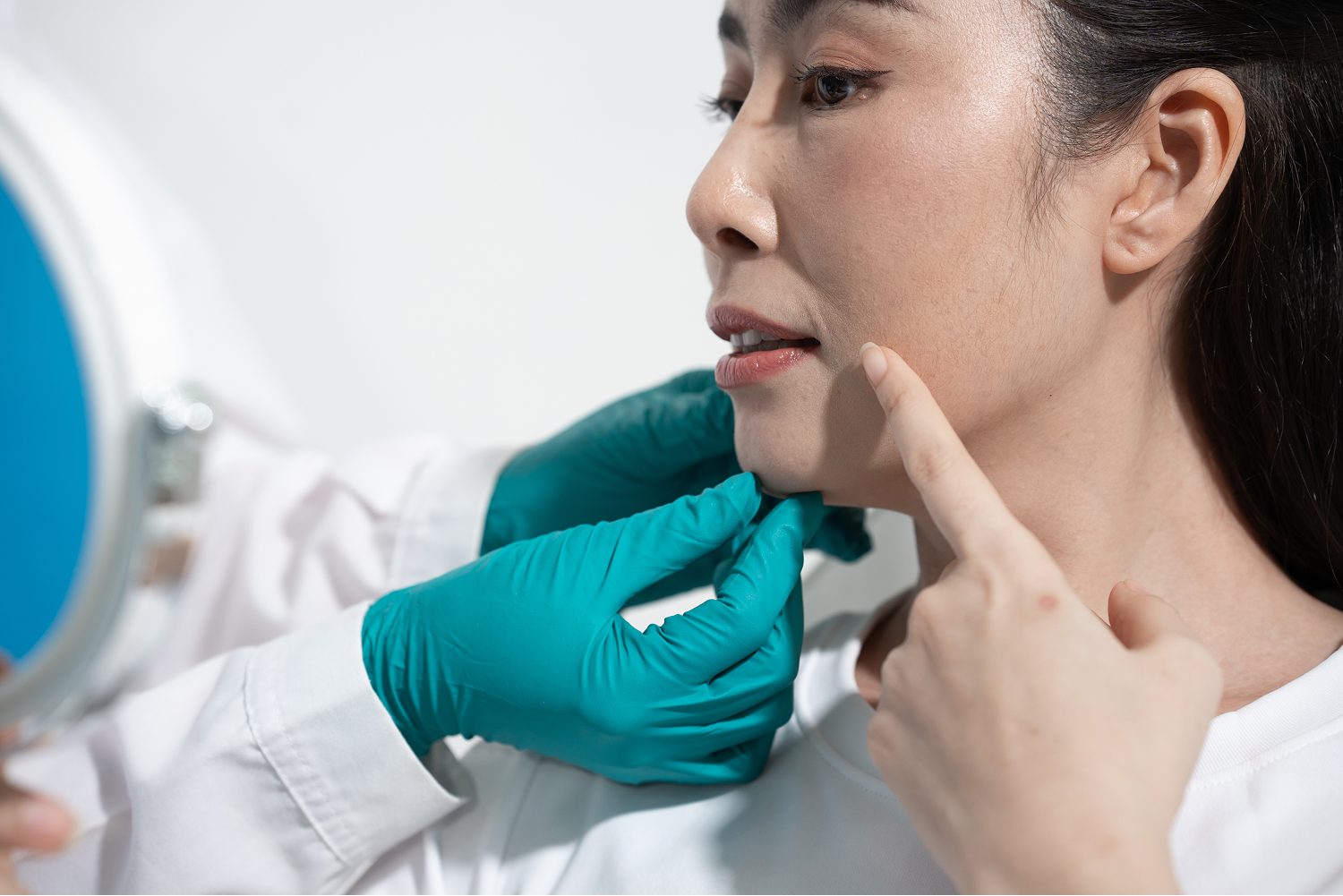 Doctor assessing a woman's jawline and skin during a consultation