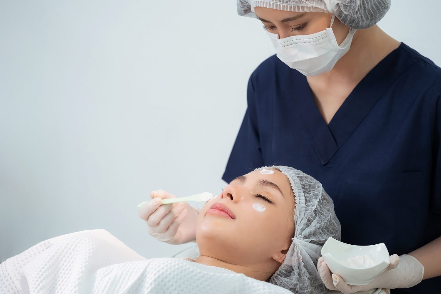 Clinician applying numbing cream to a patient's face before treatment