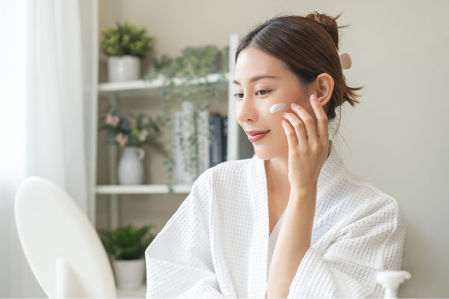 Woman applying skincare and checking her skin in a mirror
