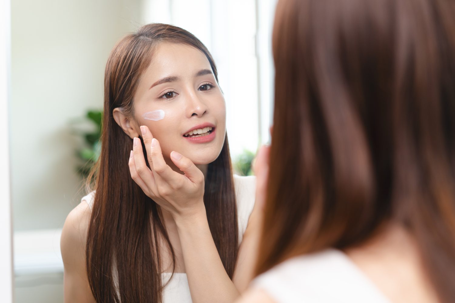 Woman applying moisturiser to her face after treatment